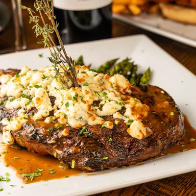Grilled steak with blue cheese and thyme garnish served with asparagus.