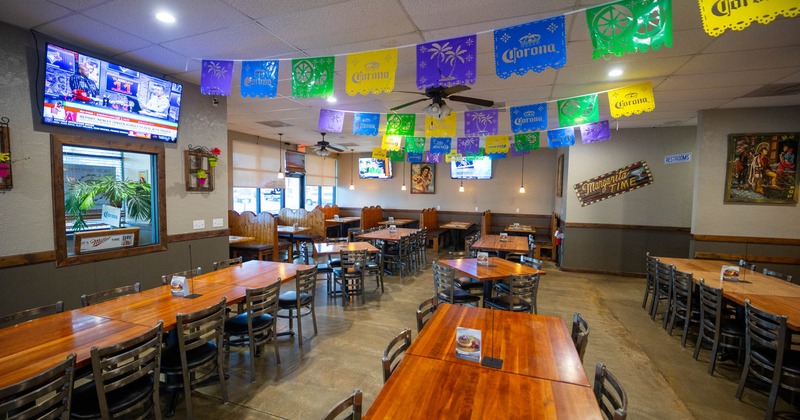 Interior, seating area, wooden top tables ready for guests, concrete flooring