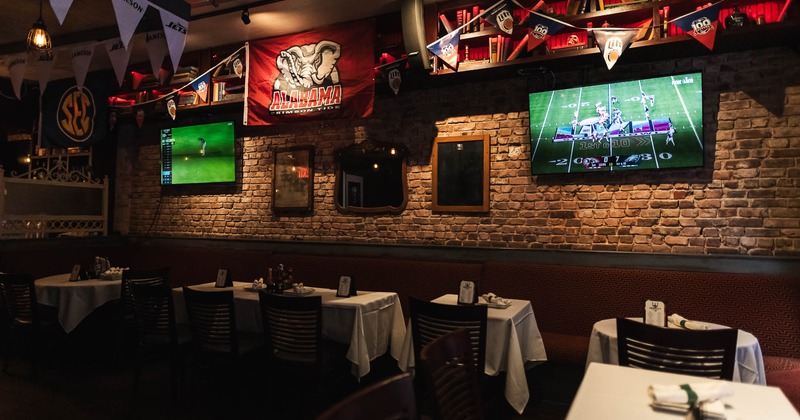 Interior, tables and chairs ready for guests with TVs on the wall