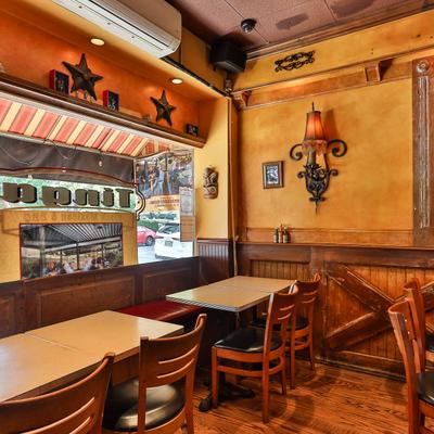 Interior with dining tables, chairs, and yellow walls with decorations.