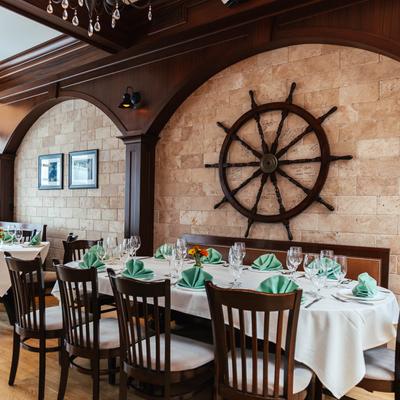 A table set with white tablecloth, tableware, glasses, napkins, and cutlery.