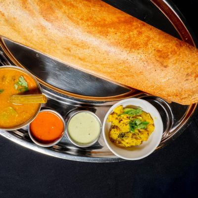 Dosa served with a lentil and vegetable stew, and various chutneys.