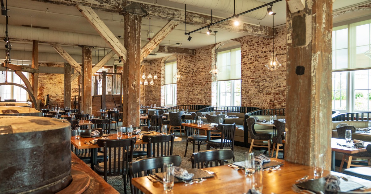 Interior, wooden tables, black chairs, and pendant lighting, with large windows