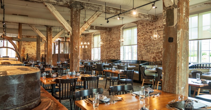Interior, wooden tables, black chairs, and pendant lighting, with large windows