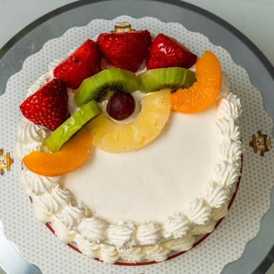 Fresh cream sponge cake topped with strawberries, kiwi, peach, and pineapple slices.