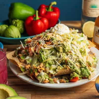 Loaded nachos topped with shredded lettuce, cheese, guacamole, and sour cream.