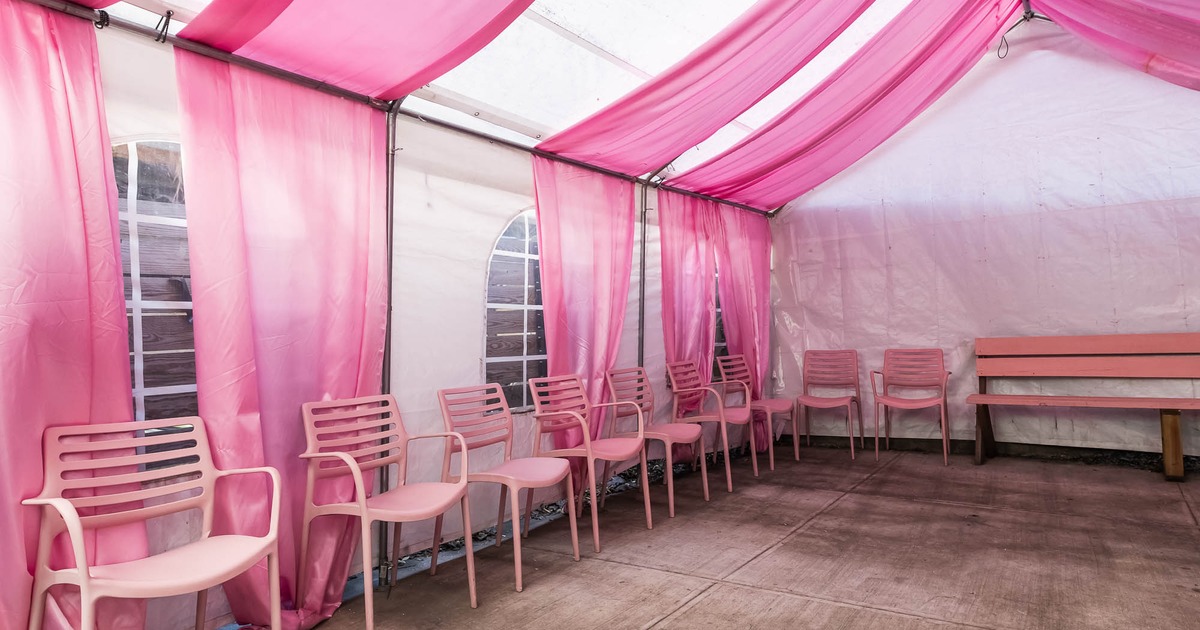 Pink and white draped tent with pink chairs