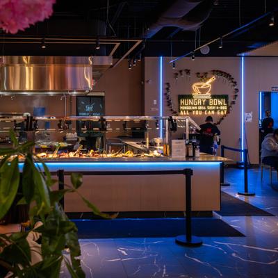 Interior featuring a buffet station, pink cherry blossom trees and neon lighting.