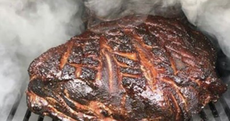 Piece of smoked beef roast cooking on a smoker grill