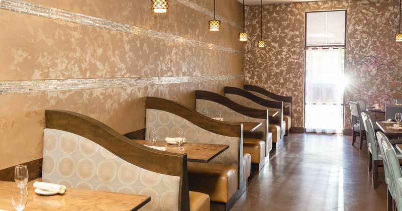 Restaurant interior with booths, pendant lighting, and a sunlit entrance