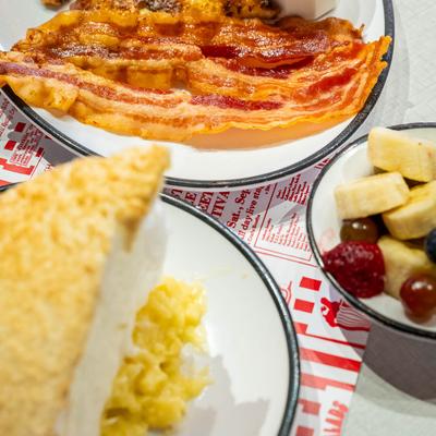 Crispy bacon strips served with a cup of fruit and a slice of coconut meringue pie.