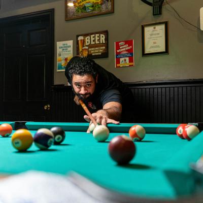Person focused on taking a shot during a game of pool.