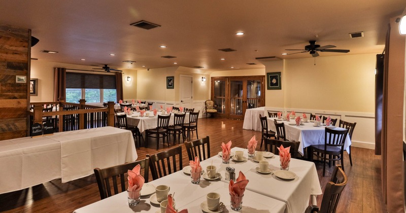 Dining area with tables set with white cloths and pink napkins