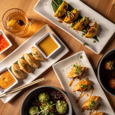 Variety of dumplings served with dipping sauces and a cocktail.