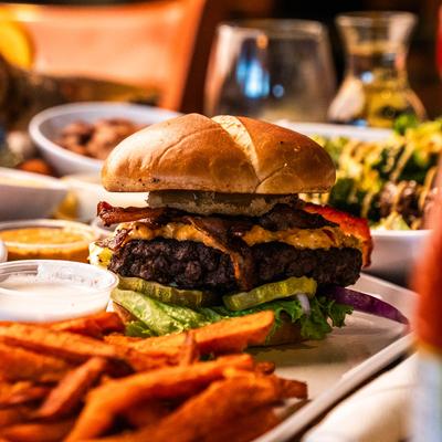 Burger with bacon and cheese served with sweet potato fries.