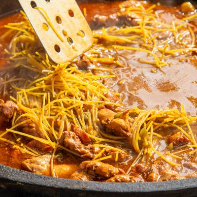 Pasta cooking in a large pot with meat.