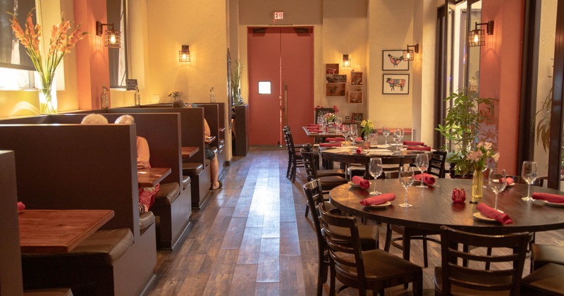 Interior, dark booths and round tables set with red napkins and glassware
