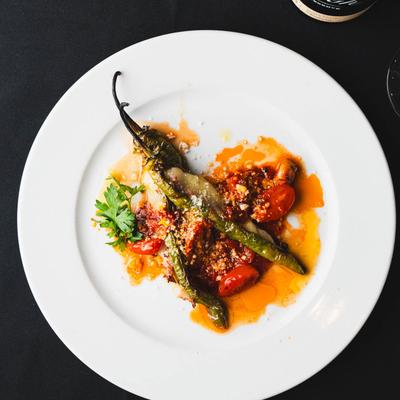 Roasted green chilies topped with tomatoes, herbs, and cheese.