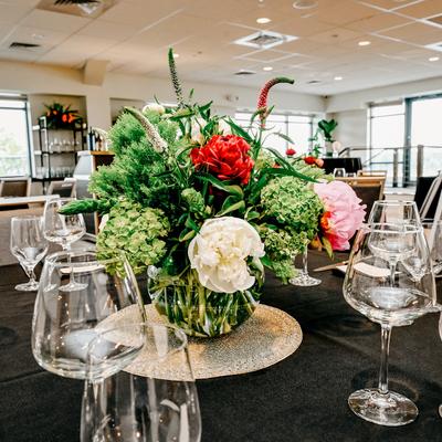 Lush floral centerpiece on a dining table with wine glasses.
