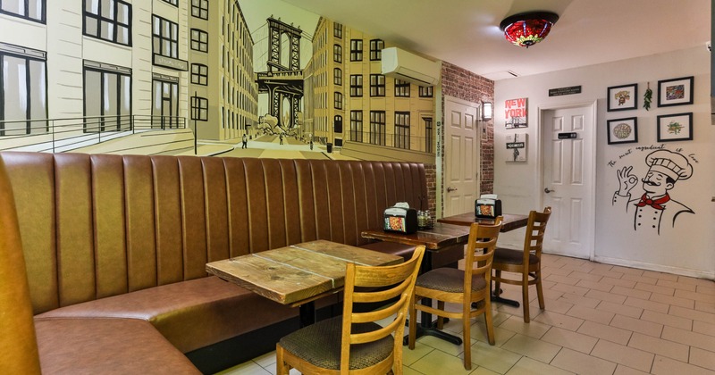 Restaurant interior with a New York-themed mural, brown booth seating, and wooden tables and chairs