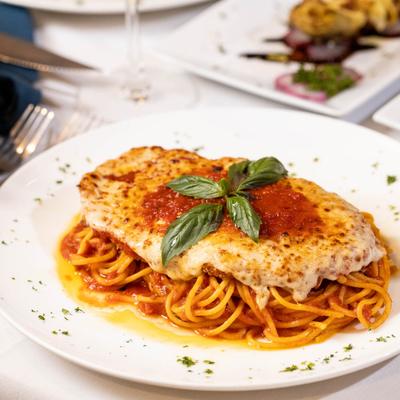 Chicken Parmigiana served over spaghetti.
