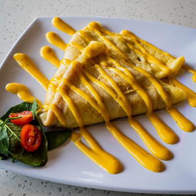 Crepe, with sauce, spinach, and grape tomato on the side.