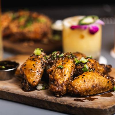 Lemon pepper wings on a wooden board with margarita drink in the back.