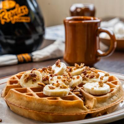 Belgian waffle topped with banana slices and crushed walnuts.