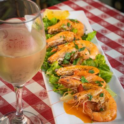 Garlic grilled shrimp with lettuce and parsley, served with a glass of white wine.
