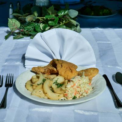 Fried fish with sides if potatoes and coleslaw.