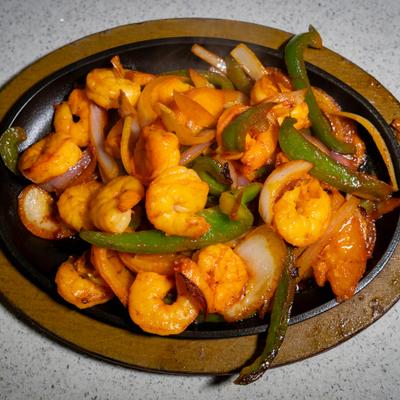 A hot skillet with shrimp fajitas.