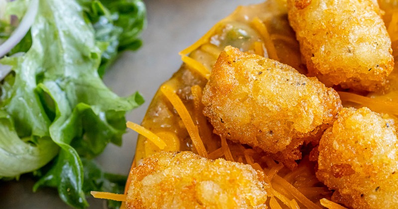 Crispy tater tots with grated cheese and a side salad