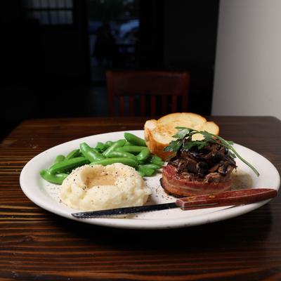 Bacon wrapped filet mignon with mash potatoes , snap peas and toasted french bread.
