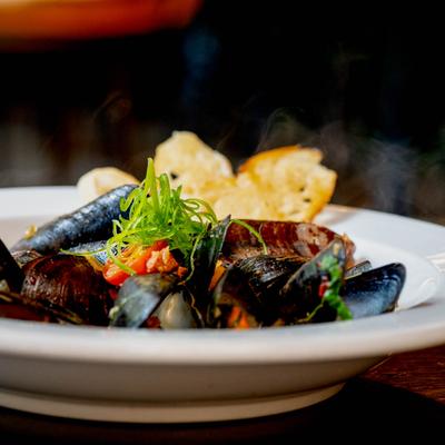 A plate of mussels served with garlic bread.