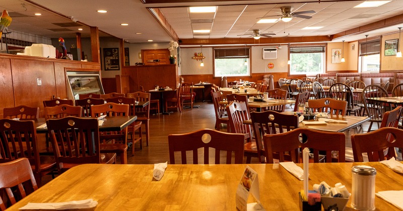 Interior of spacious, cozy, and rustic dining area with tables set for guests