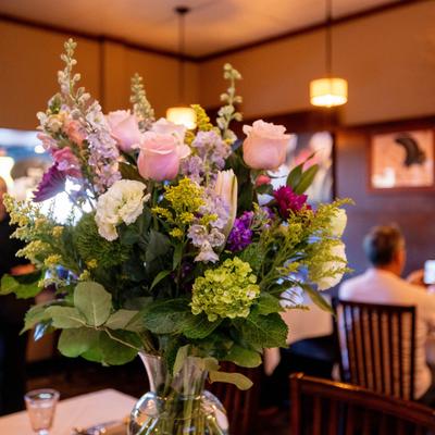 Floral arrangement featuring large light pink roses and tall white snapdragons.