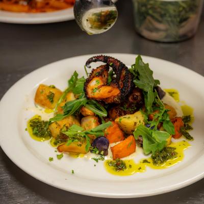 Char-grilled octopus tentacle served with roasted potatoes, arugula and herb sauce.