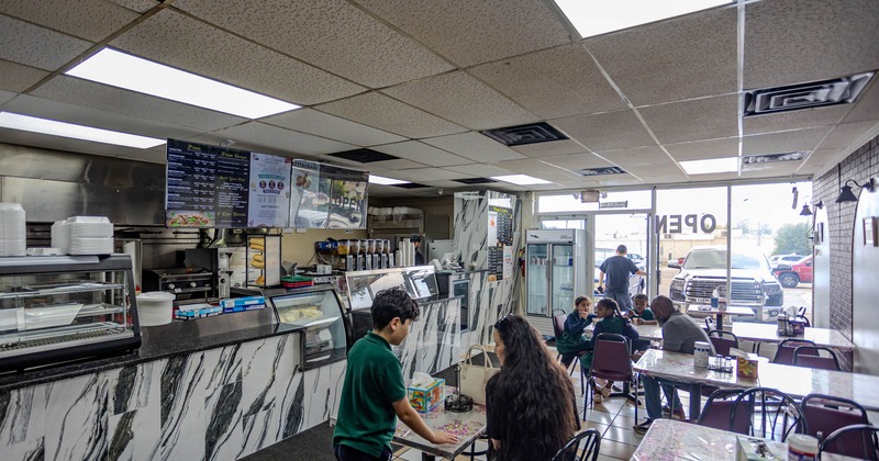 Casual diner with customers at tables, a marble-patterned counter, and a visible menu