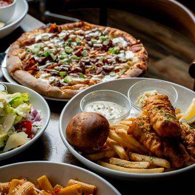 A vibrant spread featuring a pizza, fish and chips, pasta, and a salad.