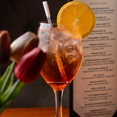 Aperol Spritz served on the table alongside a menu and flowers.