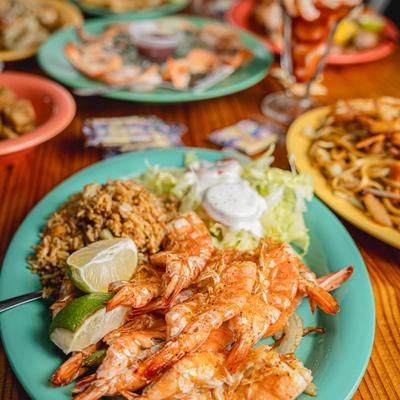 Grilled shrimp plate with various other dishes on the table.