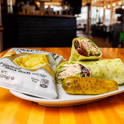 Vermont Turkey wrap served with a pickle and a bag of kettle chips.