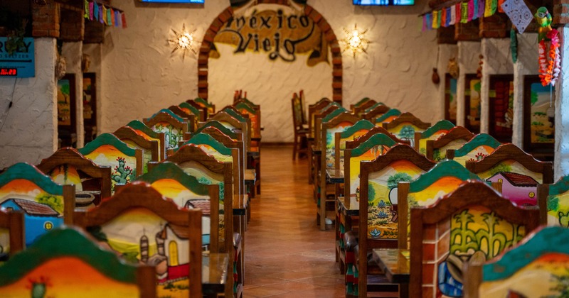 Interior of a Mexican-themed restaurant with painted chairs and rustic decor