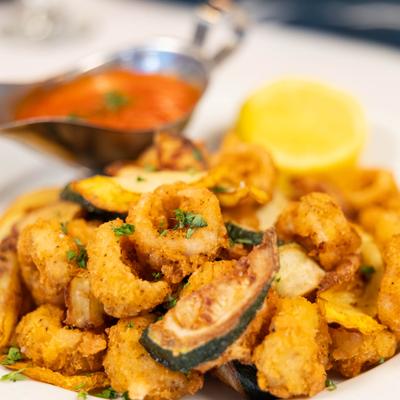 Fried calamari accompanied by sliced, fried zucchini, close-up.