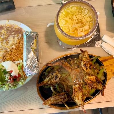 A skillet of fajitas served with a margarita and a burito.