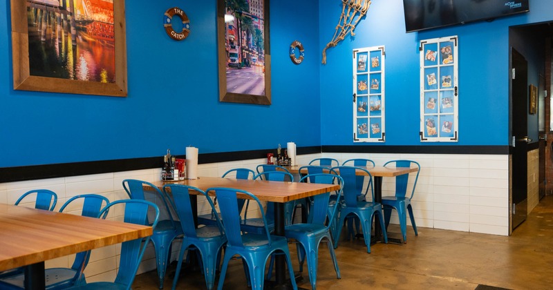 Dining area with blue chairs, wooden tables and nautical-themed decor on blue walls