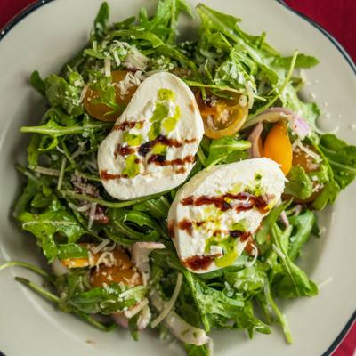 Fresh Italian salad featuring creamy burrata cheese served over a bed of arugula.