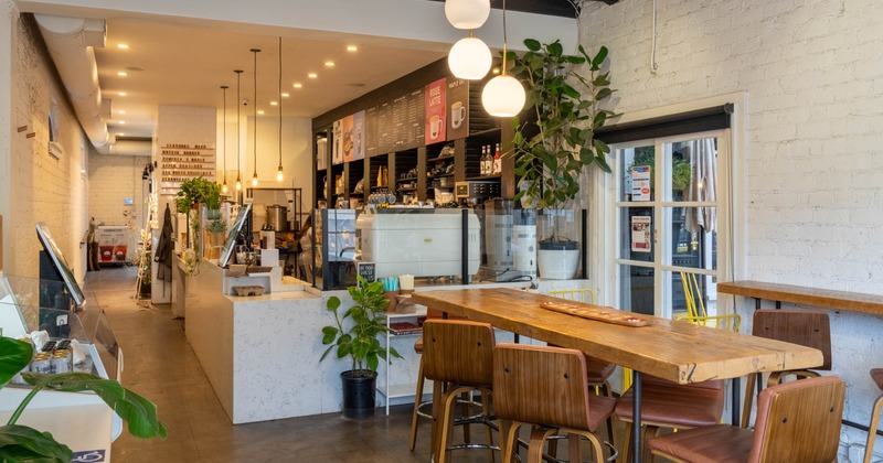 Interior of a modern cafe with a wooden communal table and pendant lights