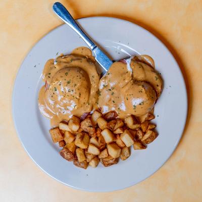 Eggs Benedict served with fried potatoes.