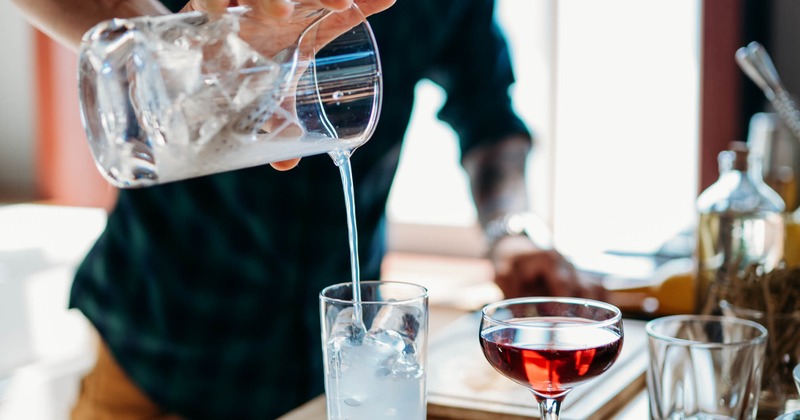 Bartender straining a cocktail from the mixing glass into a glass